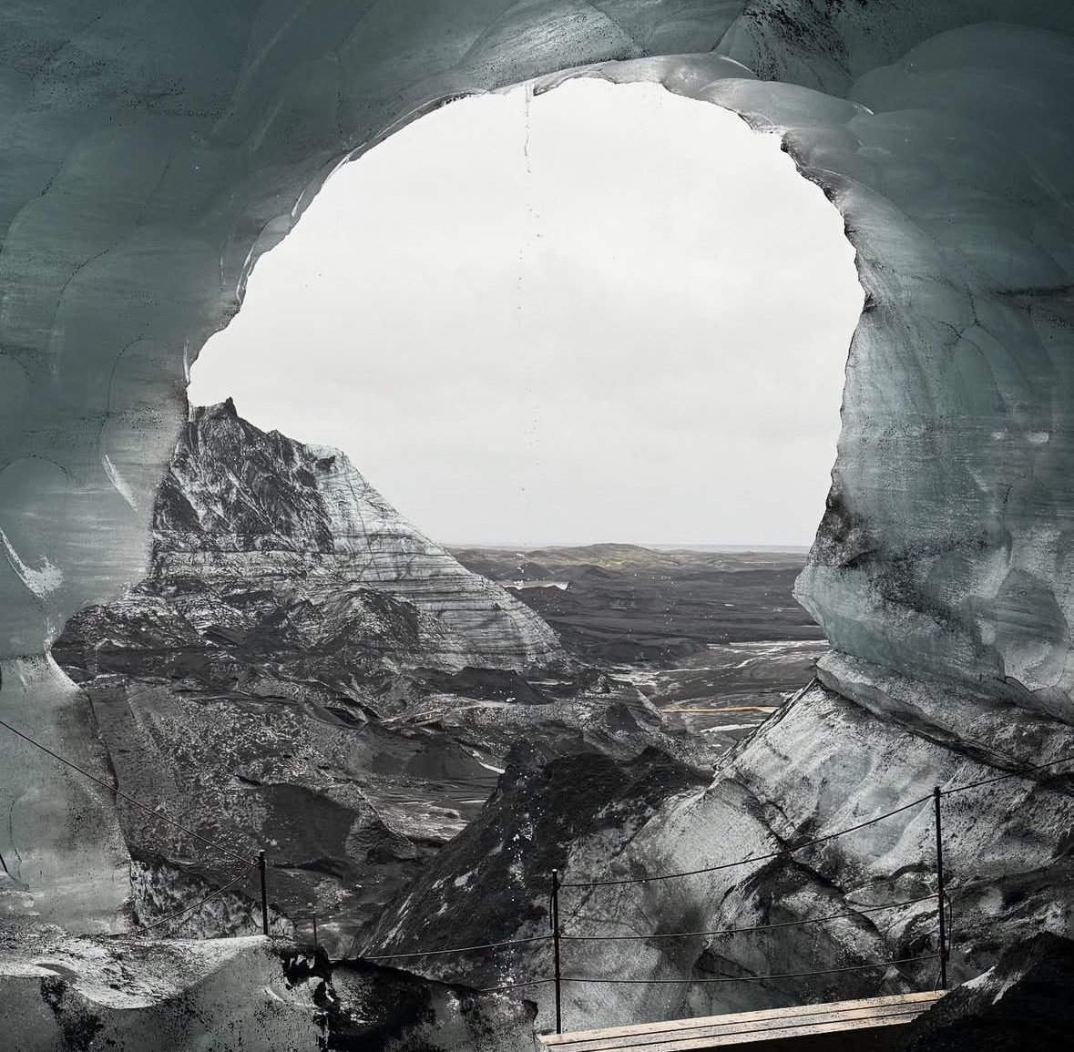 Tourists inside the Katla Ice Cave Tour exploring blue and black ice formations beneath Mýrdalsjökull glacier in Iceland